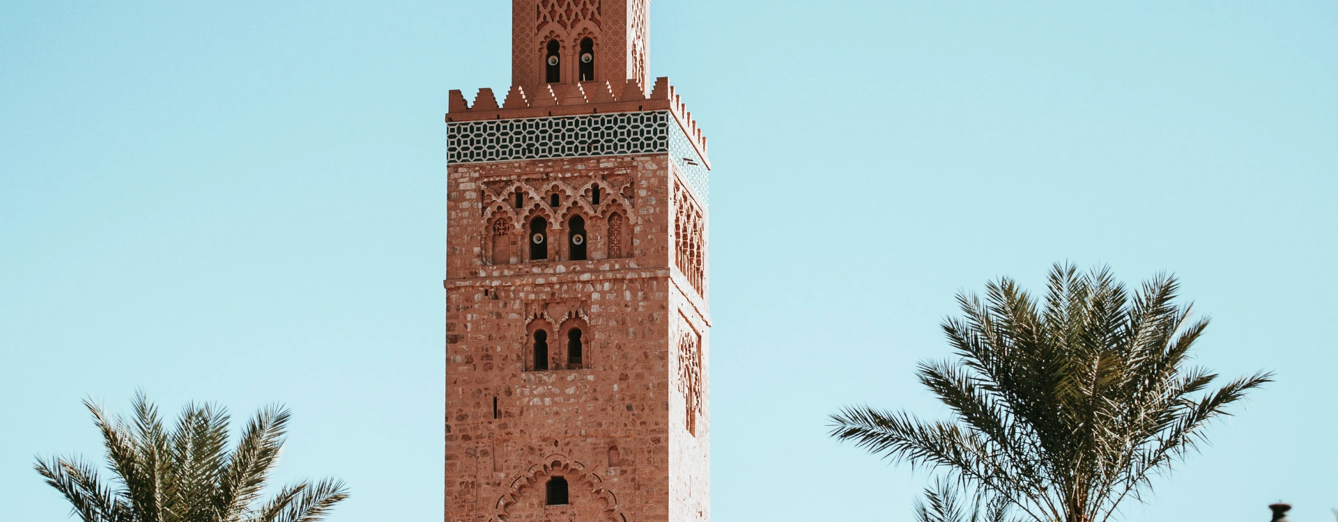view of a mosque against blue skies with palm trees